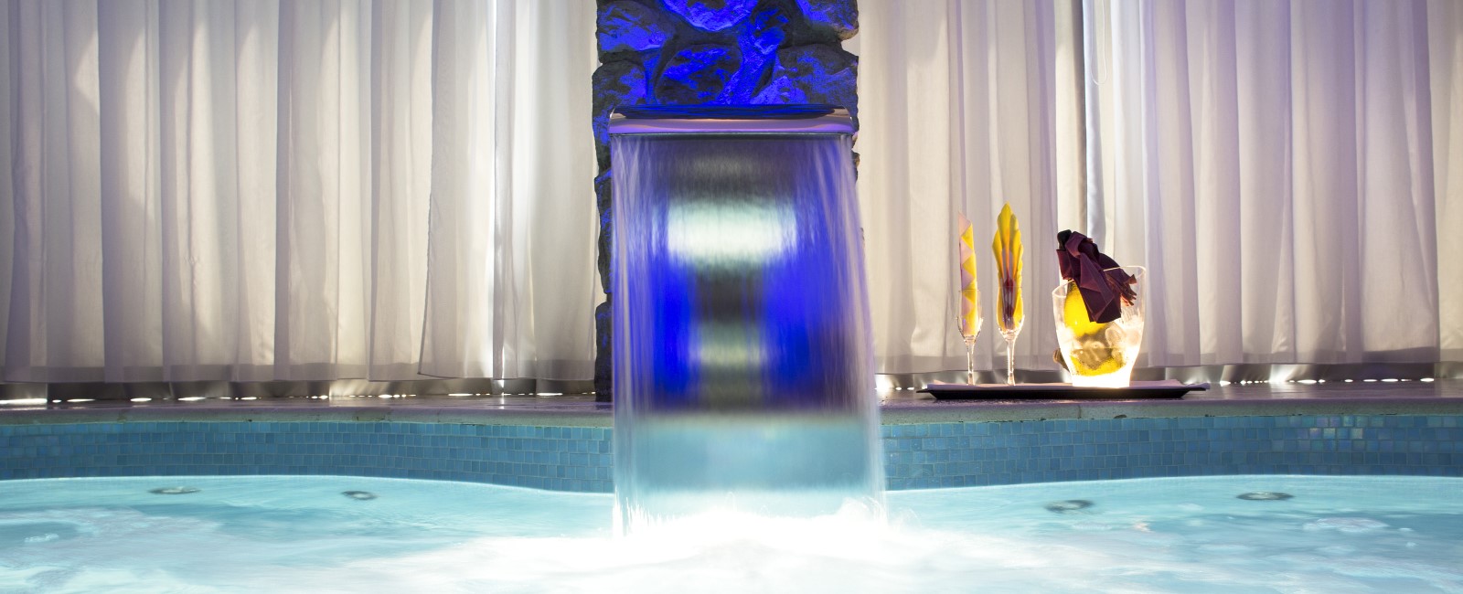 Motel K FantaSuite Antigua Motel K FantaSuite Antigua dettaglio sulla cascata della piscina idromassaggio privata in camera, bottiglia di champagne a bordo piscina, camera a tema isole dei caraibi