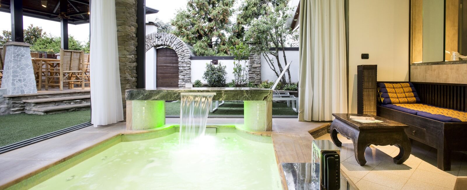 Motel K FantaSuite Thailandia Motel K FantaSuite Thailandia vista sulla piscina idromassaggio con cascata e cromoterapia, sullo sfondo si intravede il giardino esterno con le sdraio e la zona ristorazione sotto al gazebo estivo, camera a tema asiatico