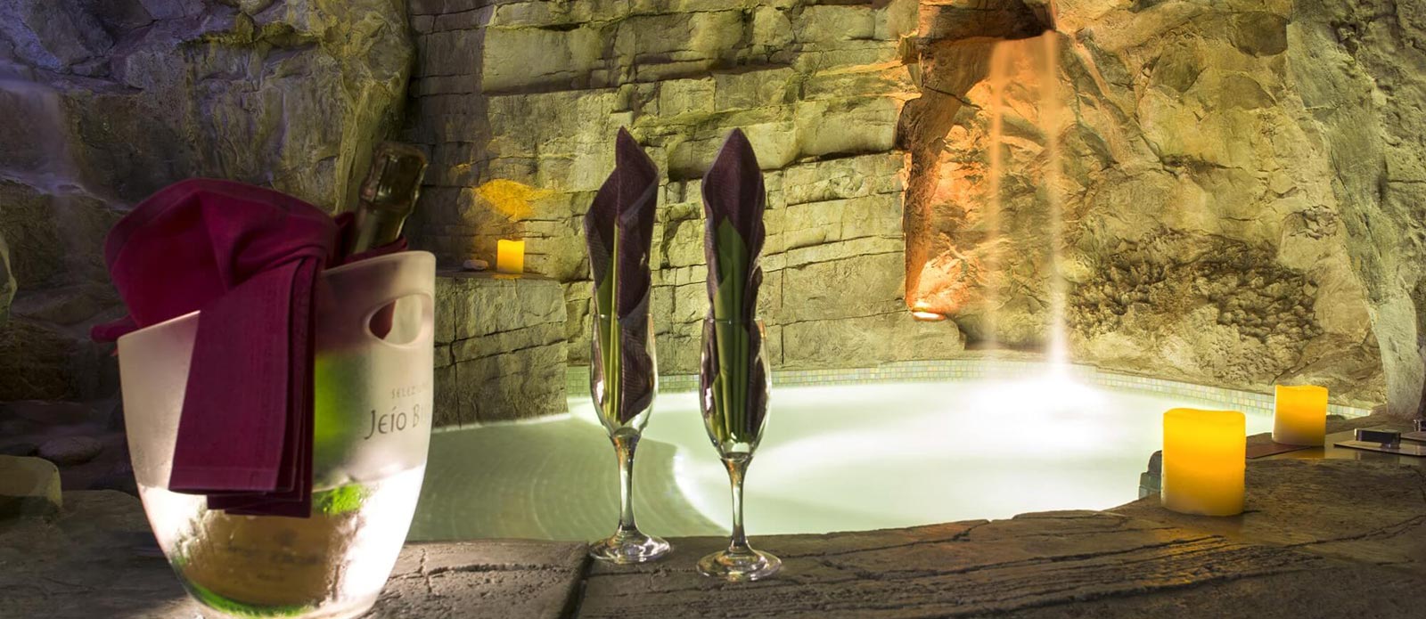 Motel K Wellness Suite Grotta Verde Motel K Wellness Suite Grotta Verde vista sulla mini piscina con idromassaggio e cascata, cromoterapia, bottiglia di champagne in secchiello del ghiaccio appoggiata a bordo piscina con 2 biccheri, servizio candele in suite camera a tema grotta verde di marina di andrano