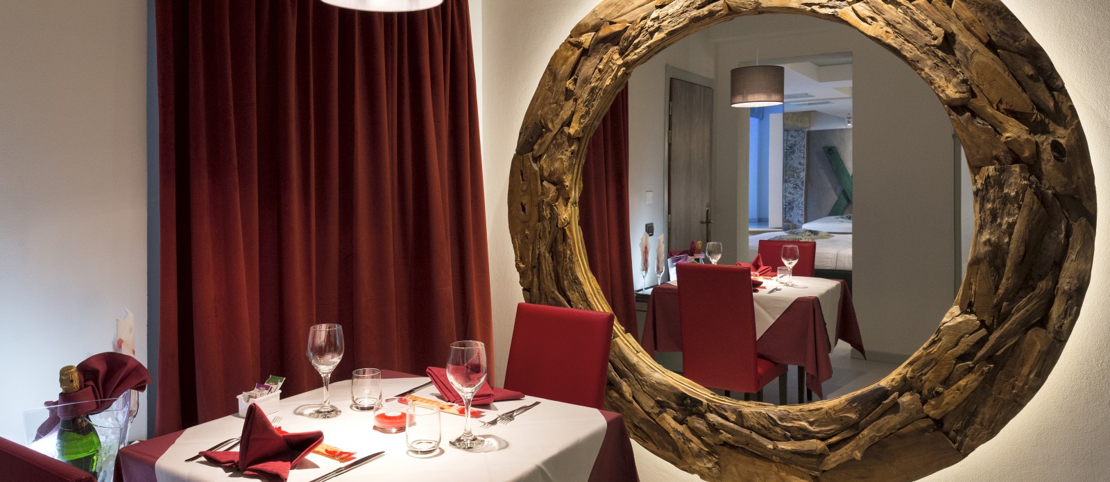 Motel K Wellness Suite Tempio Perduto Motel K Wellness Suite Tempio Perduto, vista sulla zona ristorazione privata, bottiglia di champagne in secchiello del ghiaccio, specchio rotondo che riflette verso il letto matrimoniale, camera a tema atlantide