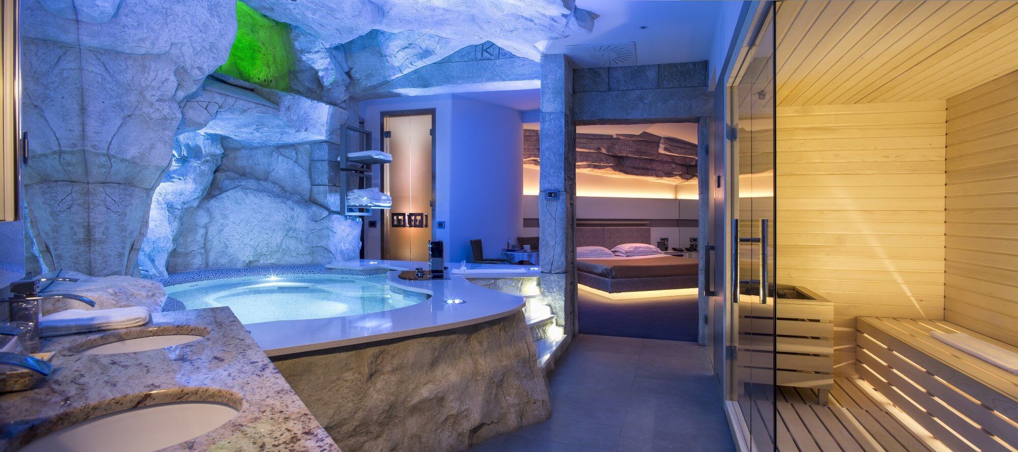 Motel K Wellness Suite Tulum Motel K Wellness Suite Tulum vista sulla mini piscina idromassaggio con cascata e cromoterapia, sauna finlandese privata in suite, sullo sfondo si intravede il letto matrimoniale, camera a tema antica civiltà azteca