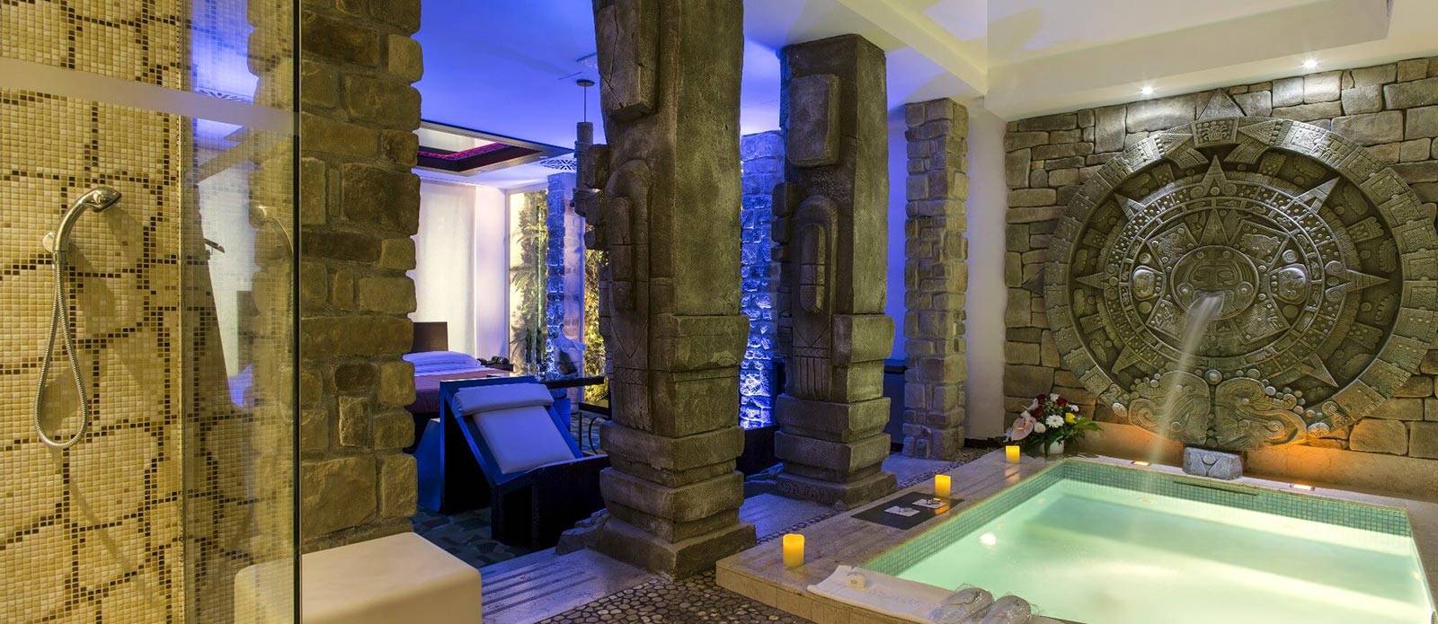 Motel K Wellness Suite Pietra del Sol vista sulla mini piscina idromassaggio con cascata, servizio candele in suite a bordo piscina, cromoterapia, sullo sfondo si intravede il letto matrimoniale con specchio a soffitto camera a tema antica civiltà azteca